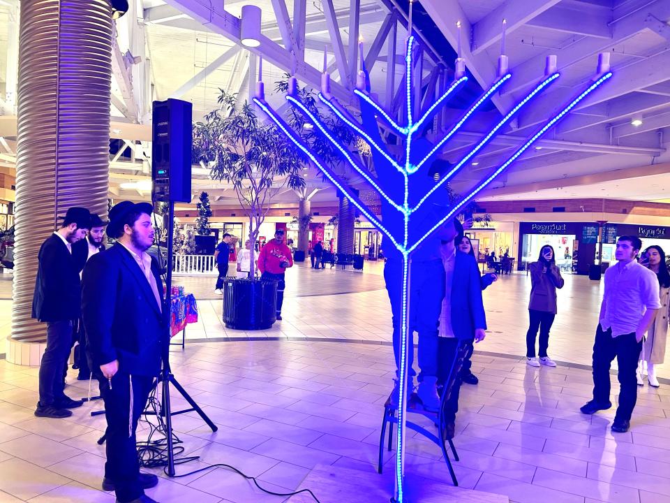 The “Roving Rabbis” light the menorah set up at Center Court of Westgate Mall in Amarillo on Tuesday during the sixth night of the eight-day Festival of Lights.