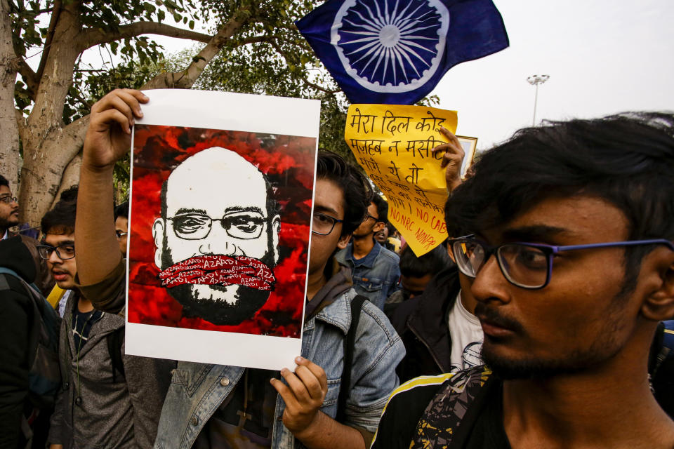 Indian students walk with a portrait of Amit Shah, Indian Home Minister, during a protest rally against the Citizenship Amendment Act, in Kolkata, India, Saturday, Dec. 21, 2019. Critics have slammed the law as a violation of India's secular constitution and have called it the latest effort by the Modi government to marginalize the country's 200 million Muslims. Modi has defended the law as a humanitarian gesture. (AP Photo/Bikas Das)