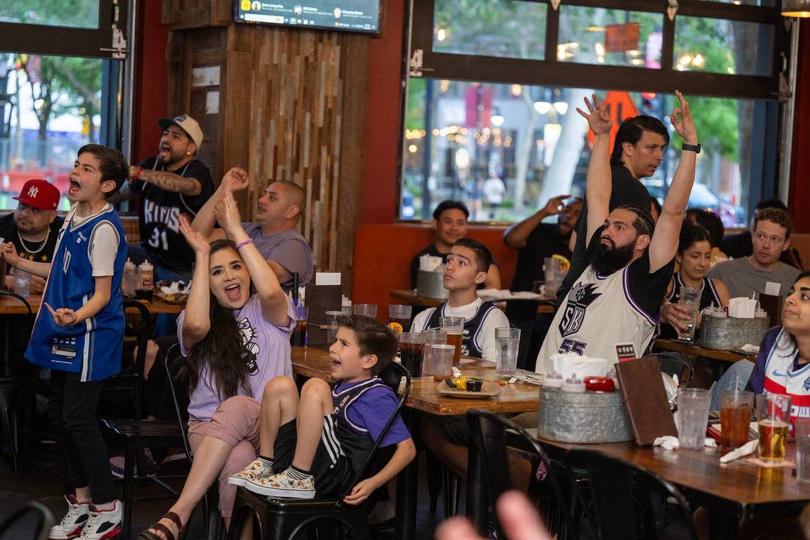 Sacramento Kings fans Adrian and Karina Dougherty cheer with their children Emmanuel, left, Nolan, center, and Darius as fans gathered to watch the play-in game between the Sacramento Kings and the New Orleans Pelicans at Sauced in downtown Sacramento on Friday.