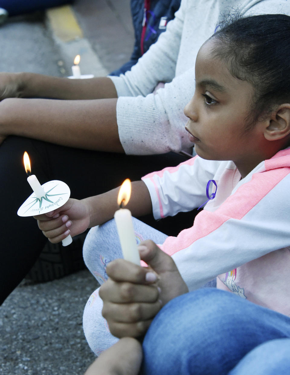 Amelia Perez, 6, holds a candle while seated with her family at the candlelight vigil for Kamille "Cupcake" McKinney in Linn Park in front of Birmingham City Hall, Wednesday, Oct. 23, 2019, in Birmingham, Ala. Police say they will charge two people with kidnapping and capital murder in the death of the 3-year-old Alabama girl whose body was found amid trash 10 days after being kidnapped outside a birthday party. (Joe Songer/The Birmingham News via AP)