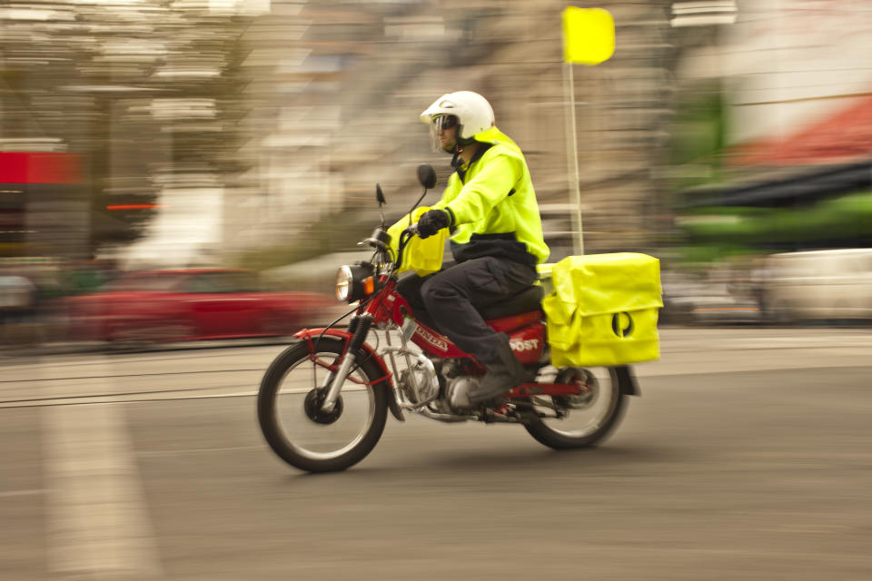 An Australia Post worker rides a motorbike.