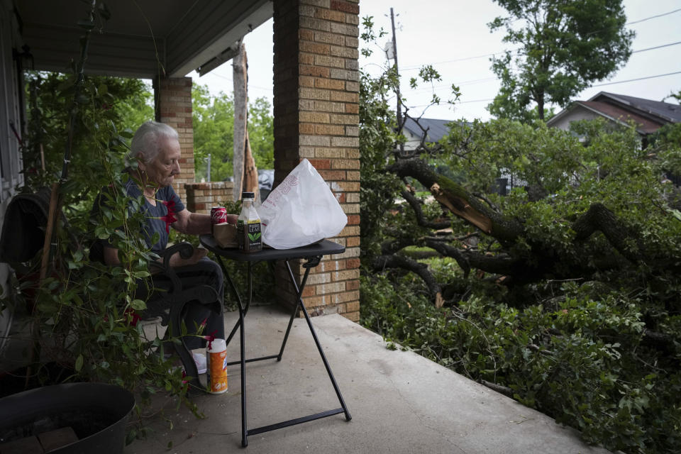 Esther Ramirez, 88, eats breakfast on her porch as her two sons and great-grandson help clean debris from her yard after a storm Friday, May 17, 2024, in Houston. The widespread destruction brought much of Houston to a standstill as crews raced to restore power and remove uprooted trees and debris. (Jon Shapley/Houston Chronicle via AP)