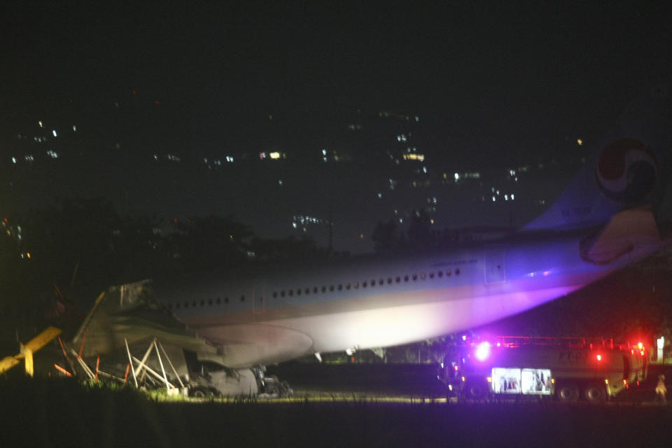 A firetruck stays beside a Korean Air Lines Co. plane after it overshot the runway at the Mactan-Cebu International Airport in Cebu, central Philippines early Monday Oct. 24, 2022. A Korean Air Lines Co. plane carrying 173 passengers and crew members overshot a runway while landing in bad weather in the central Philippines late Sunday and authorities said all those on board were safe. The airport is temporarily closed due to the stalled aircraft. (AP Photo/Juan Carlo De Vela)