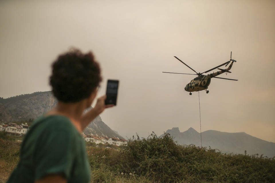 A firefighting helicopter takes water from the Aegean Sea near the Kemerkoy Power Plant, a coal-fueled power plant, in Milas, Mugla in southwest Turkey, Thursday, Aug. 5, 2021. A wildfire that reached the compound of a coal-fueled power plant in southwest Turkey and forced evacuations by boats and cars, was contained on Thursday after raging for some 11 hours, officials and media reports said. (AP Photo/Emre Tazegul)