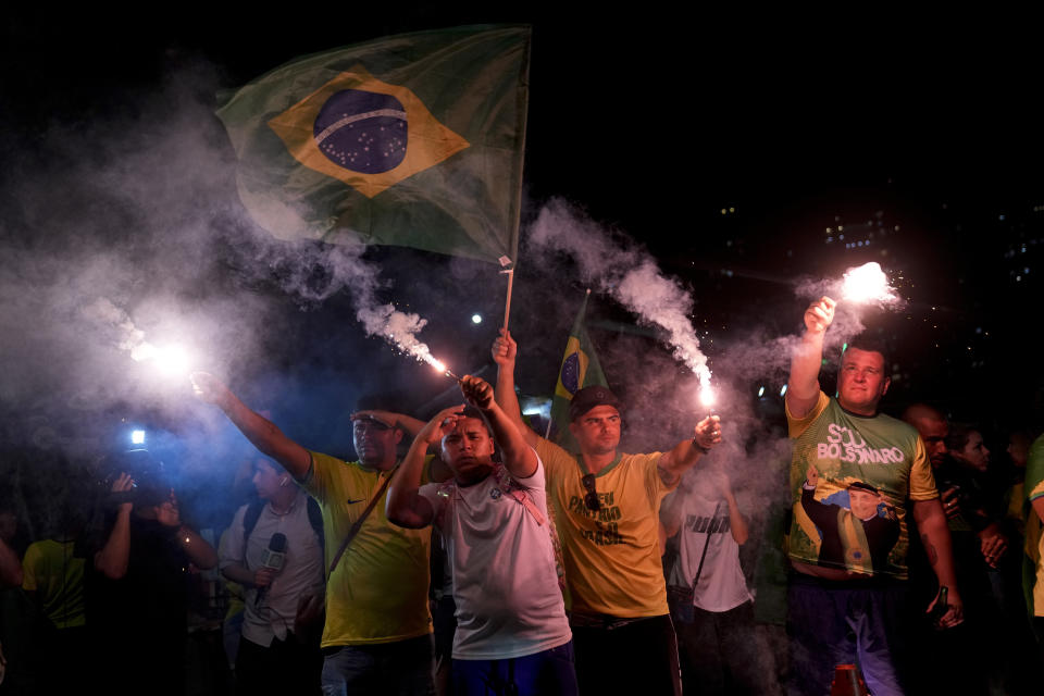 Supporters of Brazilian President Jair Bolsonaro hold flares after polls closed in the country's presidential run-off election, in Rio de Janeiro, Brazil, Sunday, Oct. 30, 2022. On Sunday, voters had to choose between incumbent Bolsonaro and his rival, former President Luiz Inacio Lula da Silva, after neither got enough support to win outright in the Oct. 2 general election. (AP Photo/Silvia Izquierdo)