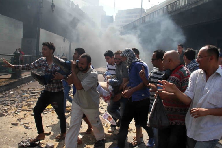 Egyptian Muslim Brotherhood supporters carry a wounded protestor in Cairo's Ramses square on August 16, 2013 after clashes broke out with police during a demonstration in support of Egypt's ousted president Mohamed Morsi