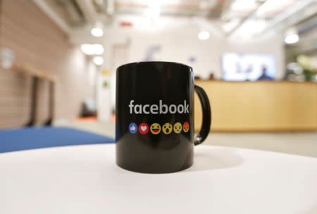 FILE PHOTO: The Facebook logo and emoticons are seen on a coffee mug at the reception of its new office in Mumbai, India May 27, 2016. REUTERS/Shailesh Andrade/File Photo