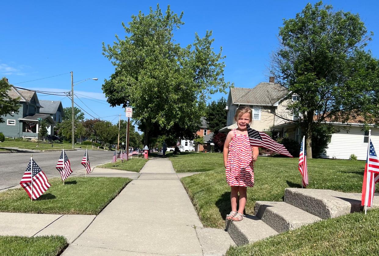 Raelyn Allgire, 4, waves a flag in honor of Memorial Day as she waits for the annual parade to pass by her house on West Oakwood Avenue on Monday.