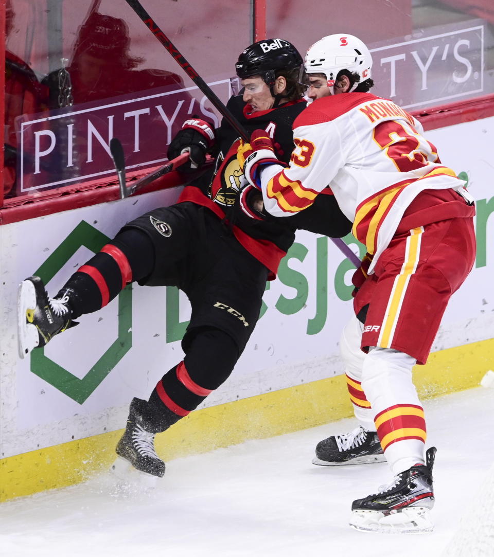 Calgary Flames centre Sean Monahan (23) puts Ottawa Senators defenseman Thomas Chabot (72) into the boards during third period NHL hockey action in Ottawa on Monday, March 1, 2021. (Sean Kilpatrick/The Canadian Press via AP)