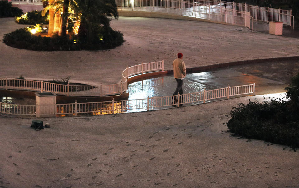 A man walks near accumulated snow along the Las Vegas Strip, Thursday, Feb. 21, 2019, in Las Vegas. A winter storm is expected to drop up to 3 inches (8 centimeters) of snow on Las Vegas' southern and western outskirts while other parts of the metro area will get rain mixed with snow. (AP Photo/John Locher)