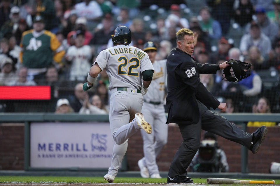 Oakland Athletics' Ramón Laureano (22) scores next to home plate umpire Jim Wolf on Jace Peterson's single against the San Francisco Giants during the fourth inning of a baseball game Wednesday, July 26, 2023, in San Francisco. (AP Photo/Godofredo A. Vásquez)