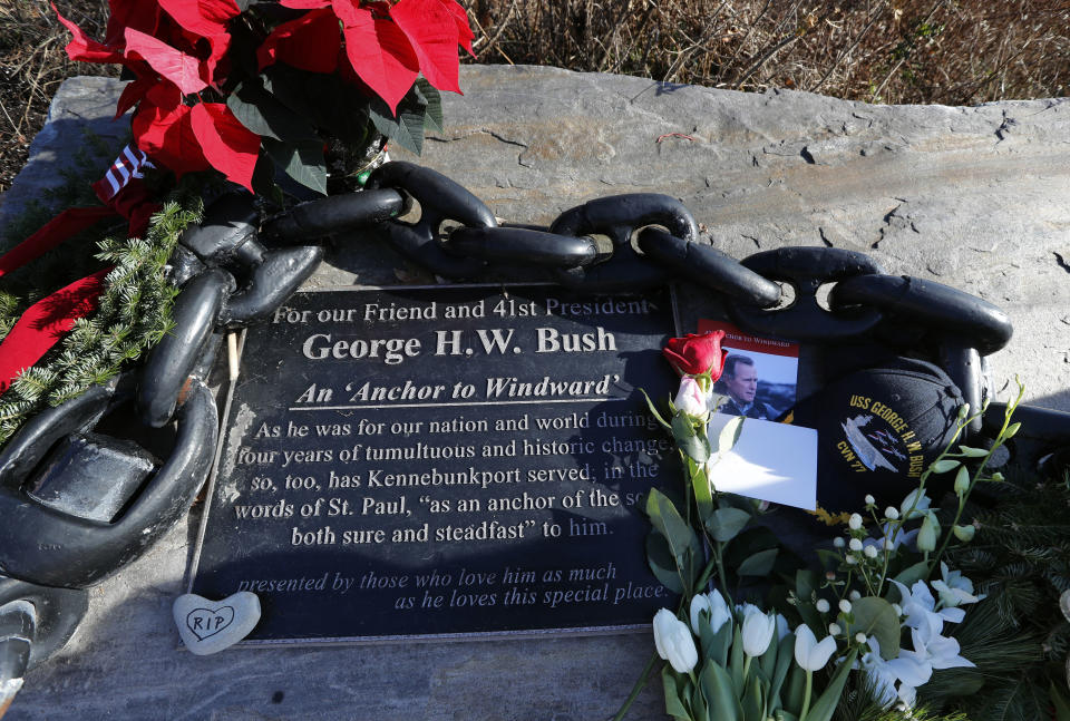 Flowers and mementoes lay near a plaque honoring former President George H. W. Bush at a makeshift memorial across from Walker's Point, the Bush's summer home, Saturday, Dec. 1, 2018, in Kennebunkport, Maine. Bush died at the age of 94 on Friday, about eight months after the death of his wife, Barbara Bush. (AP Photo/Robert F. Bukaty)