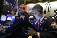Specialist Gregg Maloney, left, and trader John Panin work on the floor of the New York Stock Exchange, Friday, Dec. 13, 2019. After months of waiting, markets had a muted reaction to news Friday that the US and China had reached an initial deal on trade. (AP Photo/Richard Drew)