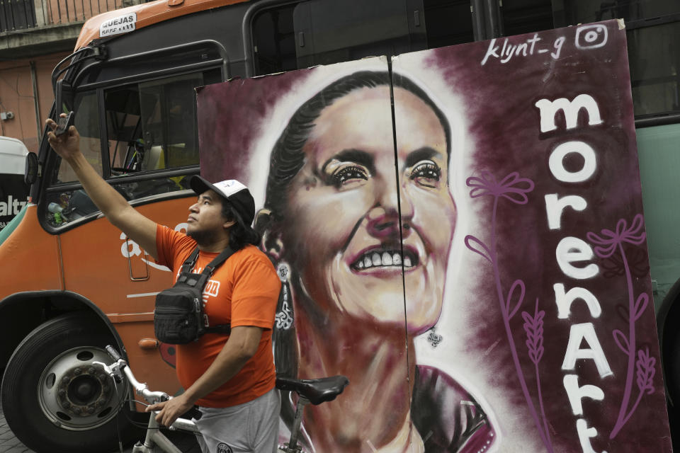 A supporter of presidential candidate Claudia Sheinbaum takes a selfie backdropped with a campaign poster during Sheinbaum's closing campaign rally at the Zocalo in Mexico City, Wednesday, May 29, 2024. (AP Photo/Matias Delacroix)