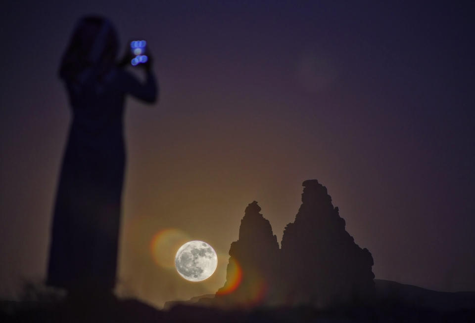 A woman takes a picture as a "supermoon" rises on Monday over the desert near Tabuk, some 1,500 kilometers away from the Saudi capital Riyadh.