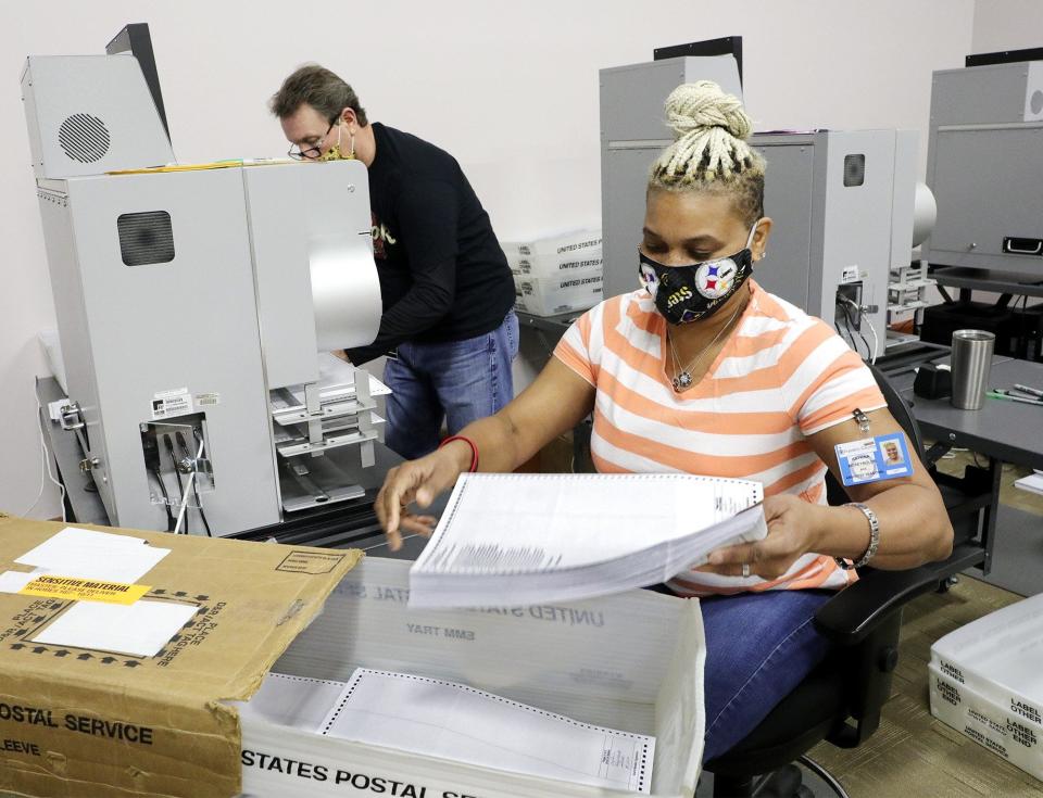 Absentee ballot clerk Katrina McReynolds, right, collects absentee ballots that Gene Shell, left, had just scanned in a ballot scanner at the Franklin County Board of Elections, 1700 Morse Road on Tuesday, April 21, 2020. The ballots were only scanned; they will not be tabulated until Tuesday.
