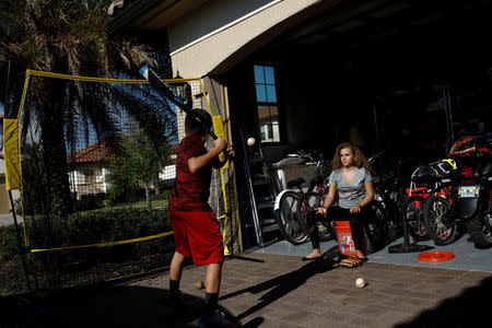 Daniela Menescal, who was injured by shrapnel during the mass shooting at Marjory Stoneman Douglas High School, helps her brother practice baseball at their house in Parkland, Florida, U.S., April 4, 2018. REUTERS/Carlos Garcia Rawlins