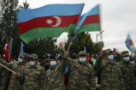 Azerbaijani soldiers wave national flags as they celebrate the transfer of the Lachin region to Azerbaijan's control, as part of a peace deal that required Armenian forces to cede the Azerbaijani territories they held outside Nagorno-Karabakh, in Aghjabadi, Azerbaijan, Tuesday, Dec. 1, 2020. Azerbaijan has completed the return of territory ceded by Armenia under a Russia-brokered peace deal that ended six weeks of fierce fighting over Nagorno-Karabakh. Azerbaijani President Ilham Aliyev hailed the restoration of control over the Lachin region and other territories as a historic achievement. (AP Photo/Emrah Gurel