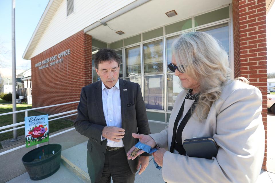 Pam Rosser Lovell shows Senator Troy Balderson the Congressional Medal of Honor awarded to her father, the late Ronald Rosser, outside of the Roseville Post Office. The building was named for Rosser during a ceremony on Monday.