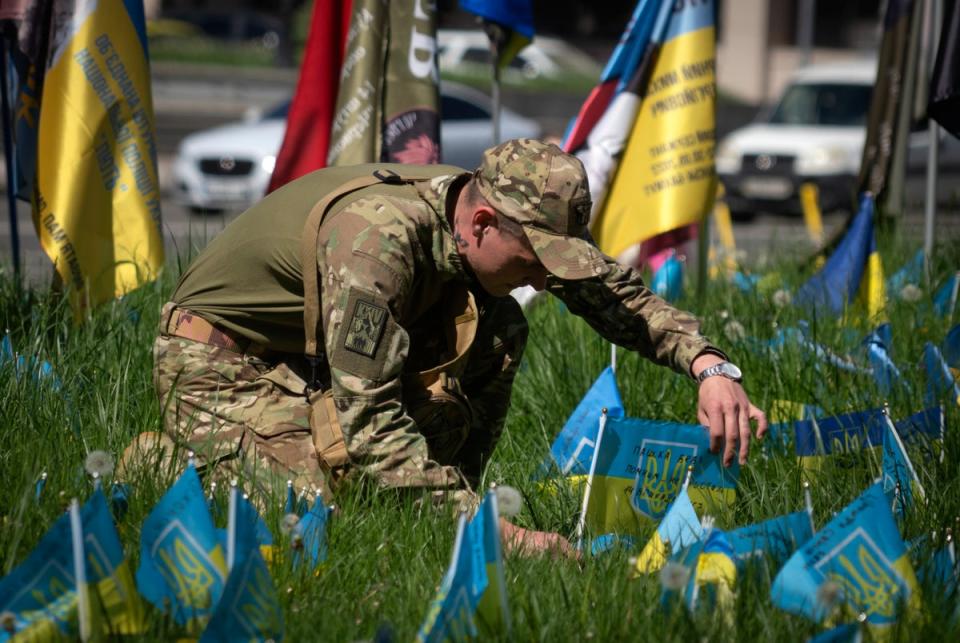 Украинский солдат устанавливает национальный флаг на лужайке на площади Независимости в Киеве (AP)