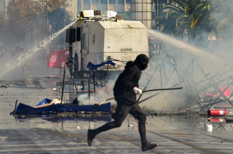 Riot police disperse demonstrators with a water cannon during clashes following a May Day march in Santiago (AFP/Martin BERNETTI)