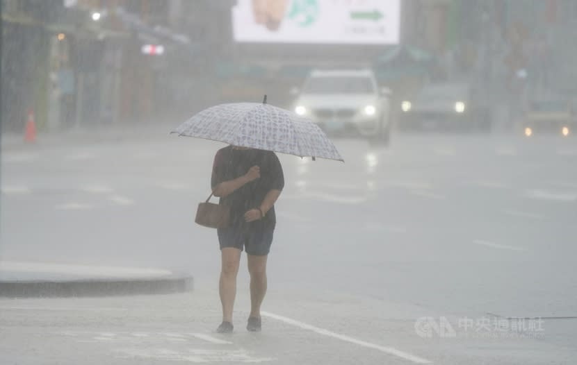 午後滂沱大雨，街頭民眾雨中撐傘低頭前進。（檔案照）