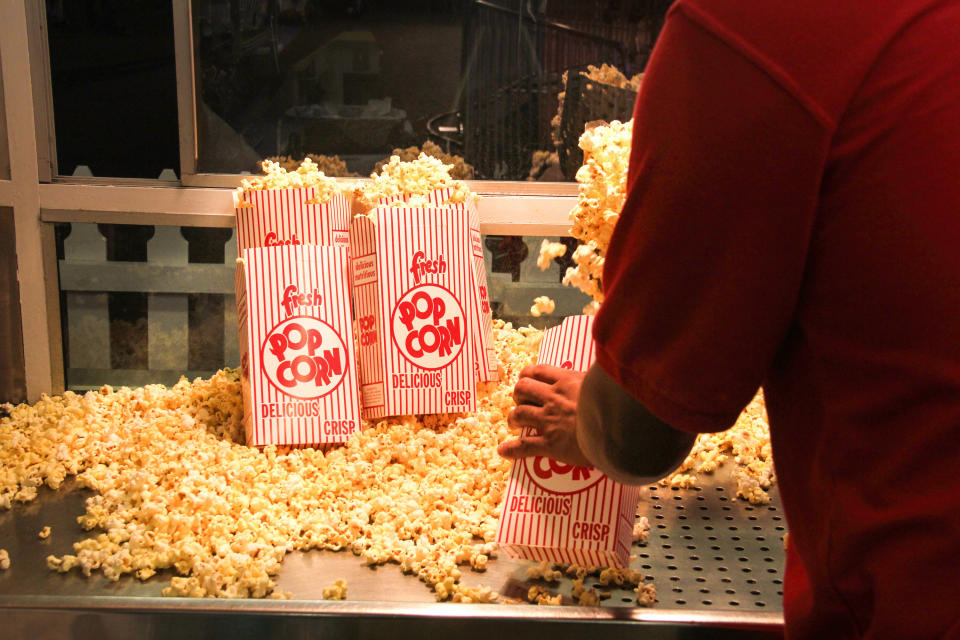 A person filling popcorn containers at the movies