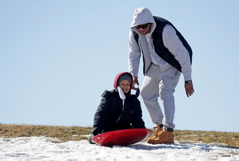 Terry Bell of Milwaukee pushes his son, Avery, 6, on a hill with some snow that hasn't melted yet at Kilbourn Reservoir Park on East North Avenue in Milwaukee on February 27, 2021.