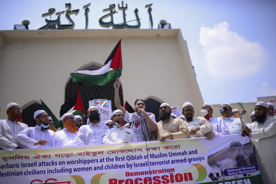 A man waves a Palestinian flag as Bangladeshi Muslims protesting against Israeli attacks on Palestinians in Gaza, gather after Eid al-Fitr prayers in front of Baitul Mukarram Mosque in Dhaka, Bangladesh, Friday, May 14, 2021. (AP Photo/Mahmud Hossain Opu)