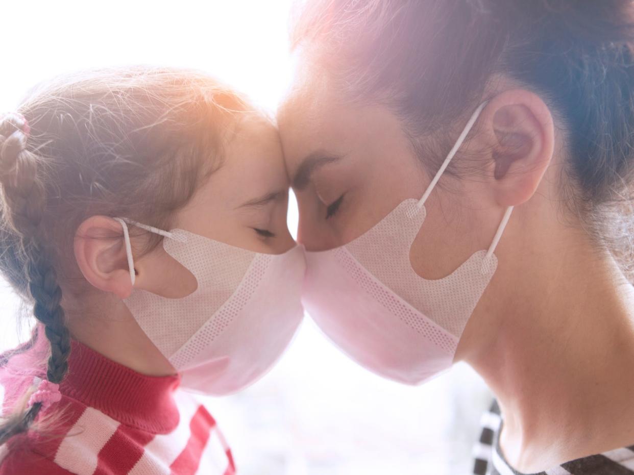 Mother and little daughter wearing surgial mask - stock photo