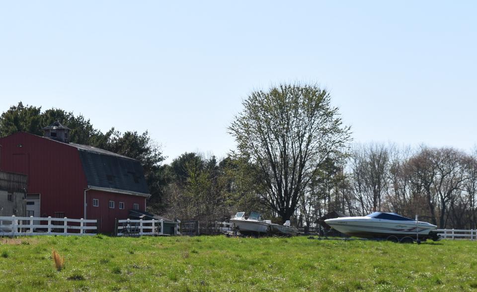 Two motorboats sit in a field outside a barn at Holly Ravine Farm in Cherry Hill.