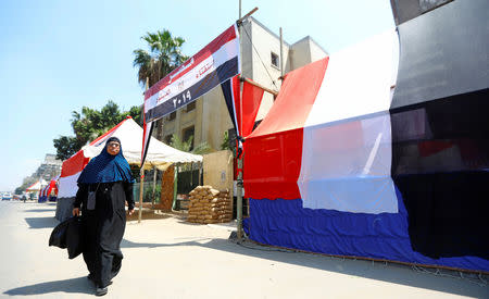 An Egyptian woman walks in front of a polling station covered from outside by Egyptian flags, during the preparations for the upcoming referendum on constitutional amendments in Cairo, Egypt April 18, 2019. REUTERS/Amr Abdallah Dalsh