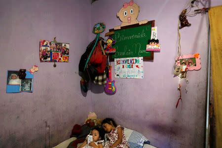 Two of Yennifer Padron and Victor Cordova's daughters play with a cellphone in the family room of the house that they share at Petare slum in Caracas, Venezuela, August 21, 2017. REUTERS/Andres Martinez Casares/Files