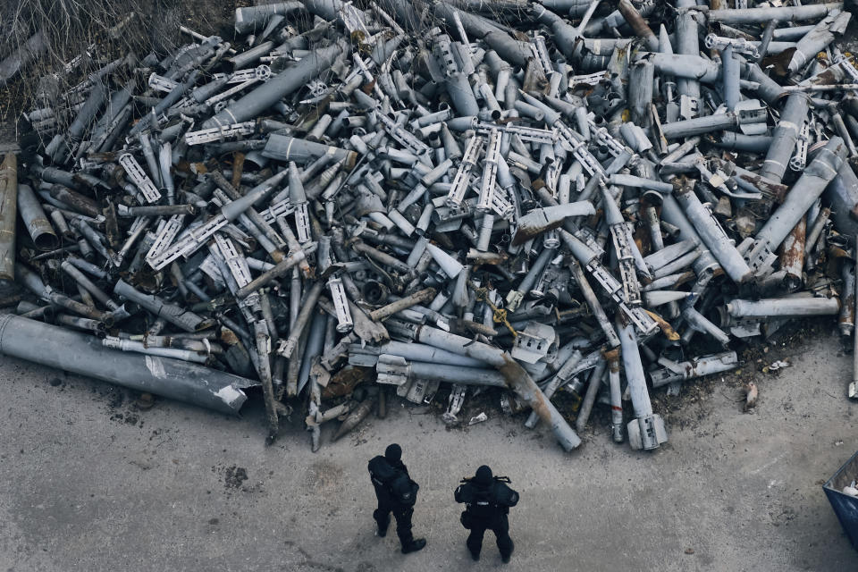 FILE - Police officers look at collected fragments of the Russian rockets that hit Kharkiv, in Kharkiv, Ukraine, Saturday, Dec. 3, 2022. With the war in Ukraine grinding through its 10th month, both sides are locked in a stalemated battle of attrition, which could set the stage for a new round of escalation. (AP Photo/Libkos, File)