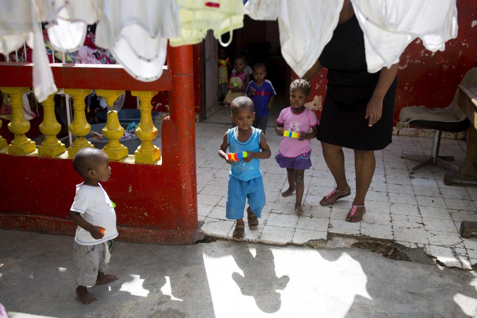 A staff member escorts orphan children to go out to play at the Nest of Hope orphanage in Port-au-Prince, Haiti on Thursday, June 28, 2018. In Haiti, the plan is to build a foster care system exclusively with parents willing to take on the task at their own expense. (AP Photo/Dieu Nalio Chery)