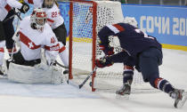 Goalkeeper Florence Schelling of Switzerland watches as Amanda Kessel of the Untied States shoot slides in for the goal during the first period of the 2014 Winter Olympics women's ice hockey game at Shayba Arena, Monday, Feb. 10, 2014, in Sochi, Russia. (AP Photo/Matt Slocum)