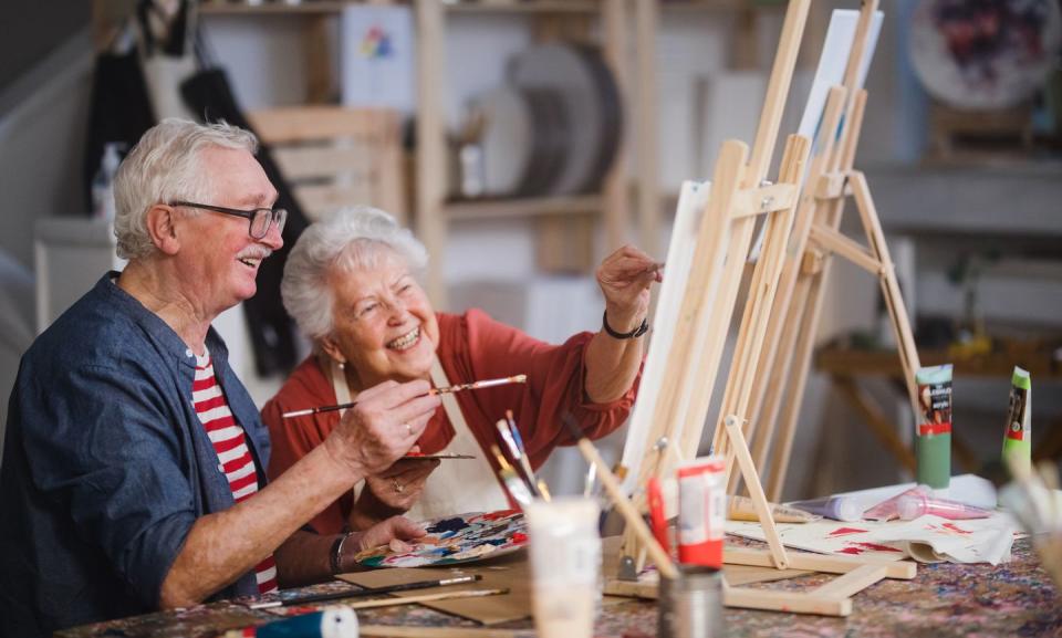 happy senior friends painting together at art class