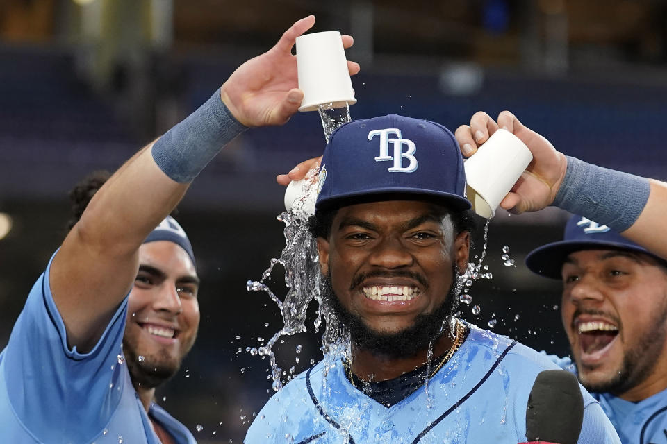 Tampa Bay Rays' Osleivis Basabe, center, reacts as Jonathan Aranda, left, and Rene Pinto pour water on his head after the Rays defeated the Colorado Rockies during a baseball game Tuesday, Aug. 22, 2023, in St. Petersburg, Fla. Basabe had a grand slam in the game. (AP Photo/Chris O'Meara)