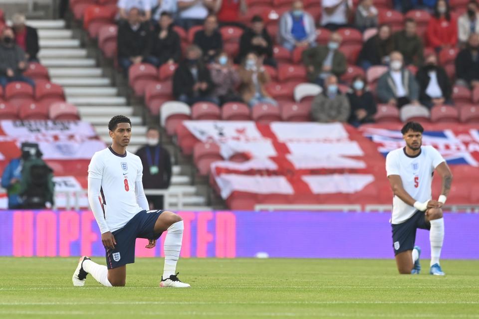 Los ingleses Jude Bellingham y Tyrone Mings se arrodillan (The FA via Getty Images)