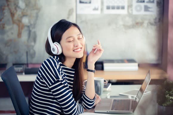 A woman listens to music on her laptop.