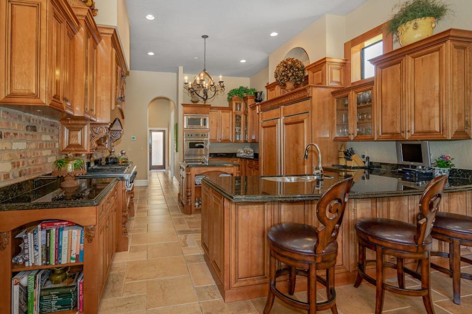 The gourmet kitchen is well equipped with custom cabinetry, granite countertops, a center-island workstation, built-in refrigerator and freezer, a Viking double oven and six-burner gas cooktop, two single-drawer dishwashers, tons of storage, a breakfast bar and kitchen nook.