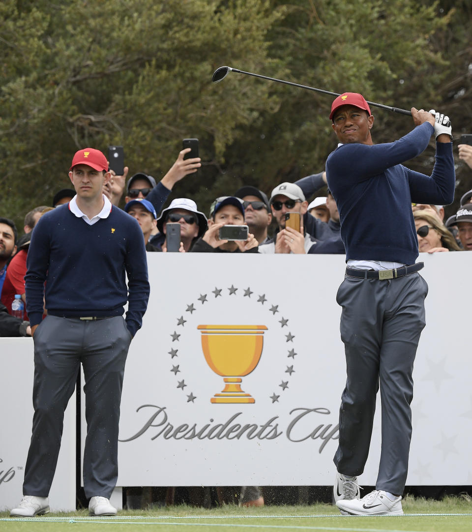 USA's Patrick Cantlay, left, watches as captain Tiger Woods tees off during a practice session ahead of the President's Cup Golf tournament in Melbourne, Tuesday, Dec. 10, 2019. (AP Photo/Andy Brownbill)