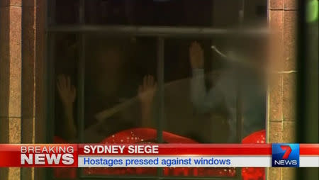 Hands are pressed up against the window of the Lindt cafe, where hostages are being held, in this still image taken from video from Australia's Seven Network on December 15, 2014. REUTERS/Reuters TV via Seven Network/Courtesy Seven Network