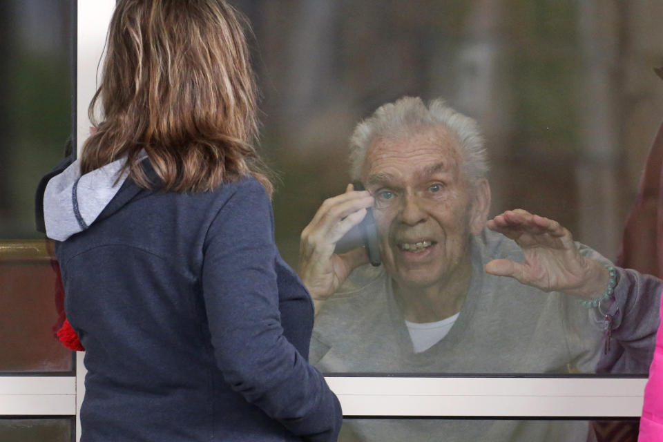 FILE - In this March 24, 2020, file photo, Kaye Knighton, 86, receives a visit from his daughter-law Darla Knighton at the Creekside Senior Living, in Bountiful, Utah. Window visits help seniors connect to families despite coronavirus restrictions. At greater risk from COVID-19, some seniors now face added anxiety due to delays obtaining Medicare coverage. (AP Photo/Rick Bowmer, File)