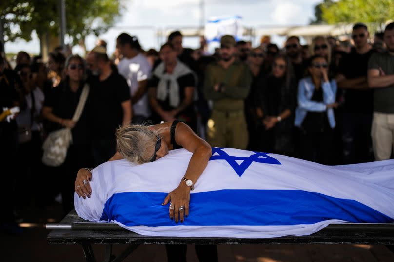 A mother cries over her son&apos;s body covered with the Israeli flag at Pardes Haim cemetery in Kfar Saba, near Tel Aviv, October 2023
