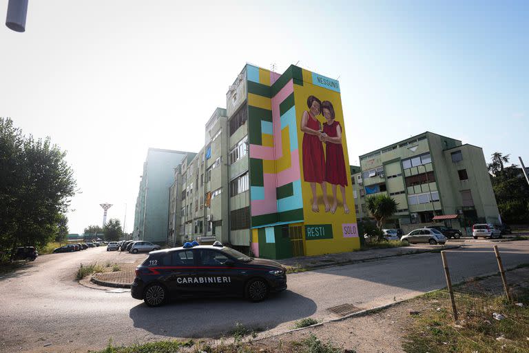 Una patrulla de la policía circula por el Parco Verde de Caivano, donde puede verse un mural de dos niñas que dice 