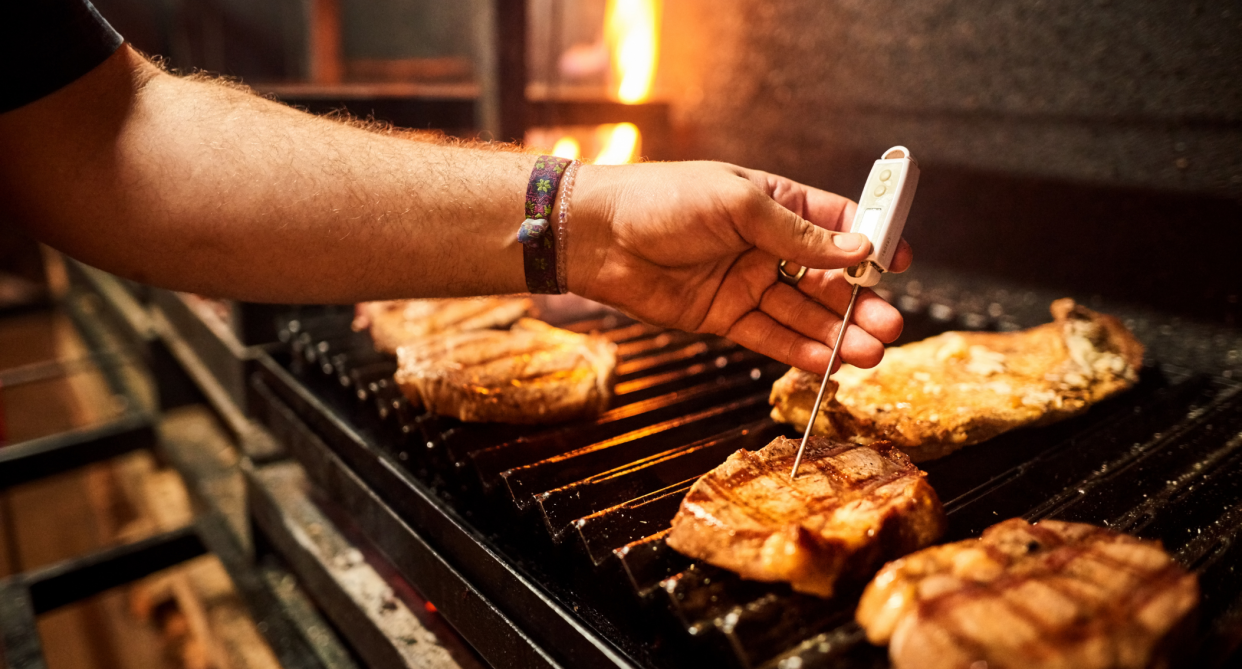 man's hand holding thermometer on steak on bbq, meat thermometer 