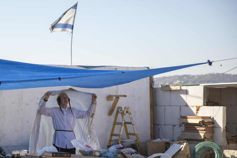 An Israeli settler prays at the outpost of Eviatar near the northern Palestinian West Bank town of Nablus, Sunday, June 27, 2021. Palestinians from the West Bank town of Beita have been holding regular protests against Eviatar, the nearby Jewish settlement outpost that was rapidly established last month. The Palestinians say it was established on their farmland. At least four protesters have been killed in clashes with Israeli troops. (AP Photo/Ariel Schalit)