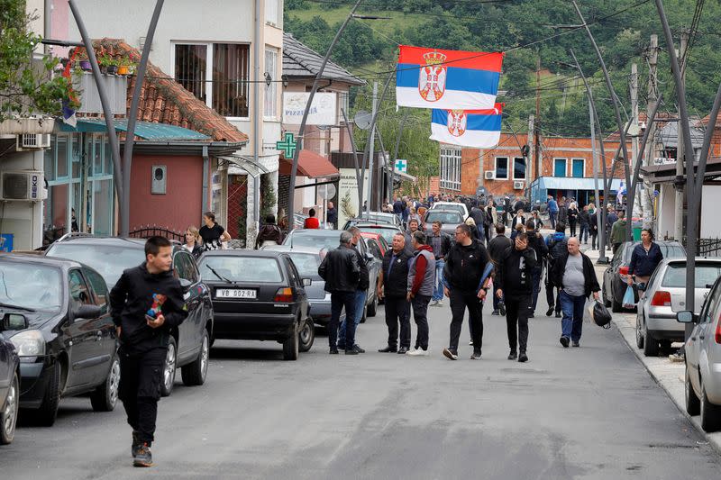 People walk along a street, as Serbian flags are displayed, in Zubin Potok