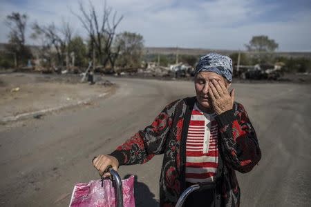 A woman cries along a street in the village of Lutugine just outside Luhanks, eastern Ukraine, September 14, 2014. REUTERS/Marko Djurica